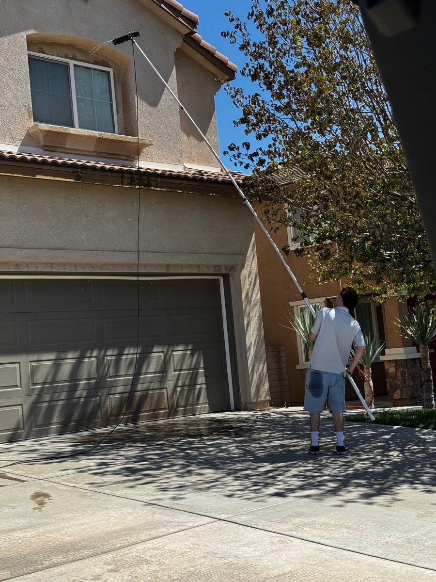 Technician using a water-fed pole to clean a gutter line from the ground